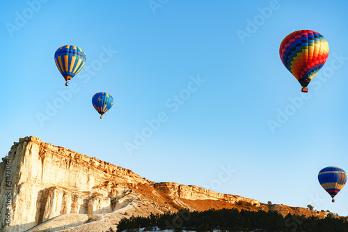 Colorful air balloons flying in clear sky near huge white mountain