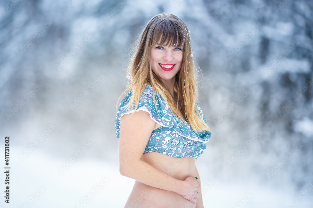 Beautiful smiling confident young woman pretty face in bikini looking at camera and posing alone at snowy forest Beautiful smiling confident young woman pretty face in bikini looking at camera and posing alone at snowy forest