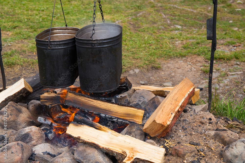 Camping food is cooked in a pot over a fire. Camping food is cooked in a pot over a fire.