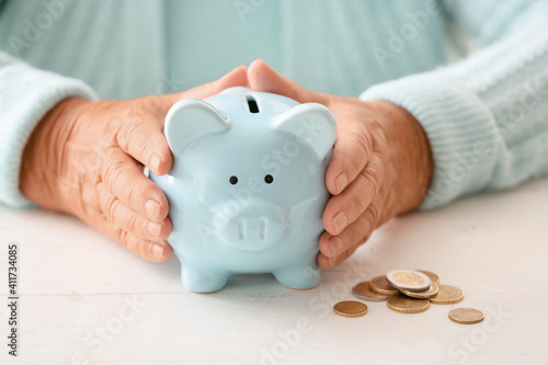 Senior woman with piggy bank at table. Concept of pension photo