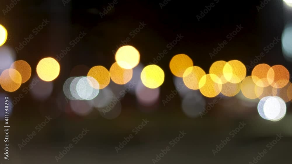 The round colorful bokeh of car and traffic lights of night city. Beautiful glittering bokeh in dark blurry background at night. Blurry background for intro.