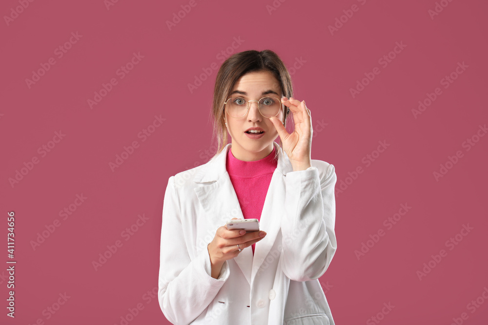 Surprised young woman with mobile phone on color background Surprised young woman with mobile phone on color background