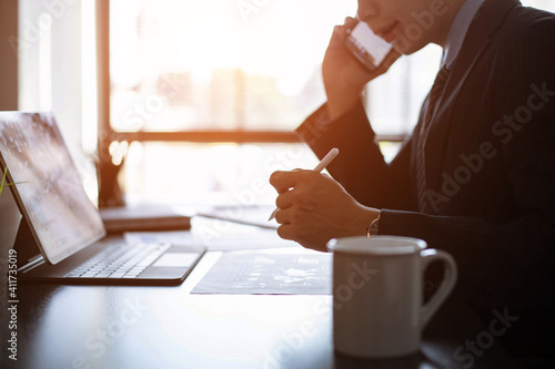 Tableau sur toile Young Asian businessman Sitting and working at a desk With market analysis sheet
