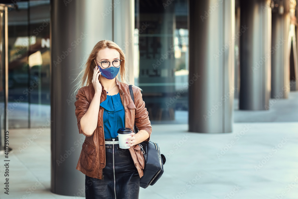 Fototapeta premium Woman wearing face mask talking on phone outdoor while commuting