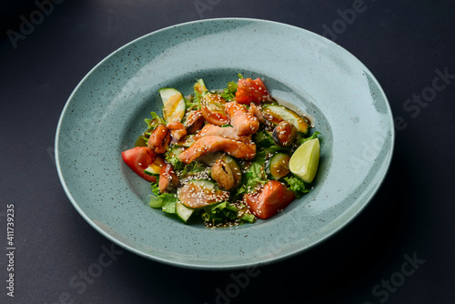 Salad with fish. Fresh vegetable salad with salmon fish fillet and sesame seeds on top. Asian cuisine concept.
