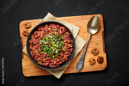 Lobio in black bowl on dark slate table top. Georgian cuisine bean stew dish. Top view