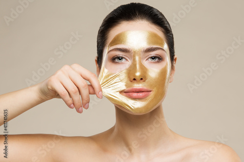 Woman peel off Gold Facial Mask. Collagen Golden Anti Aging Wrinkle Lifting Mask. Spa Beauty Treatment photo