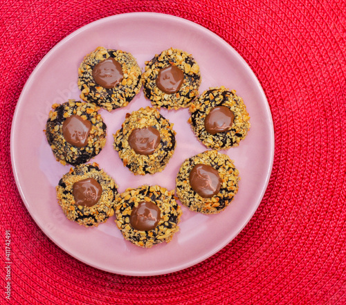 Brown Cookies with hazelnuts and peanut brittle on red background photo