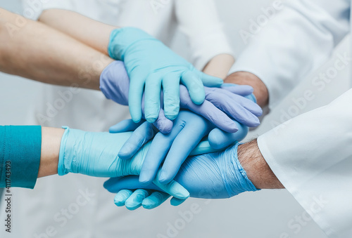 Team of young doctors stacking hands in blue gloves indoor.  medical teamwork.