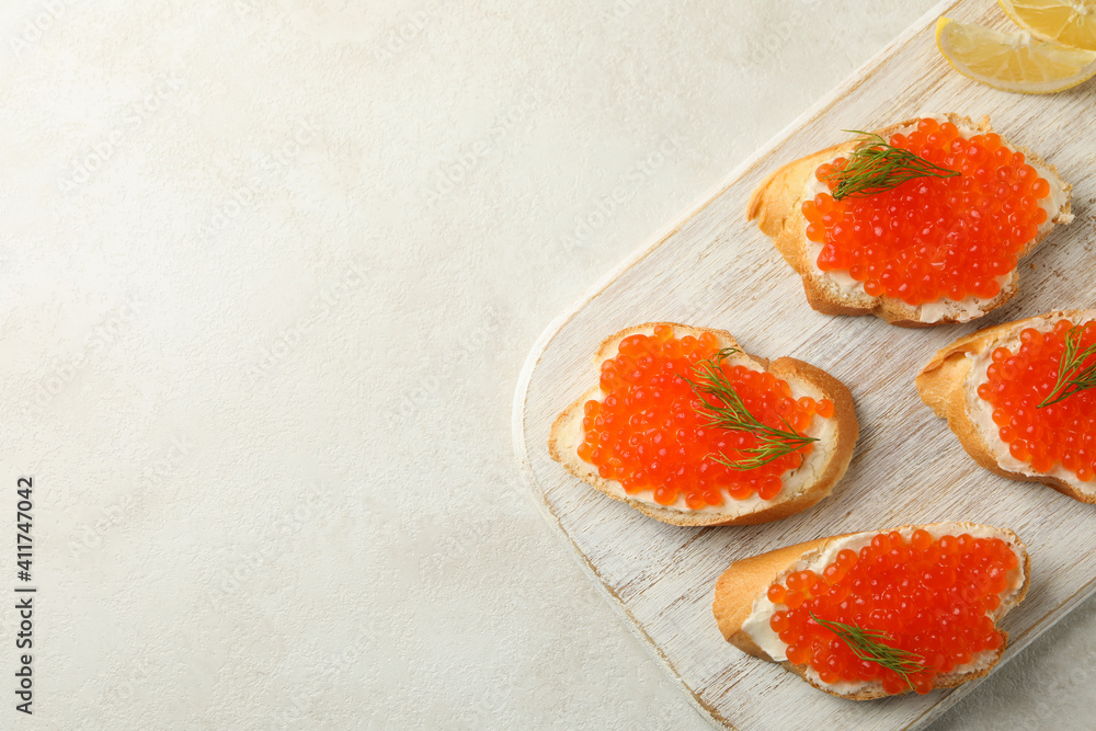 Wooden board with sandwiches with red caviar on white textured background Wooden board with sandwiches with red caviar on white textured background