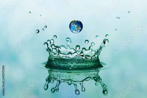 Green water splash in crown shape and falling drop with earth im