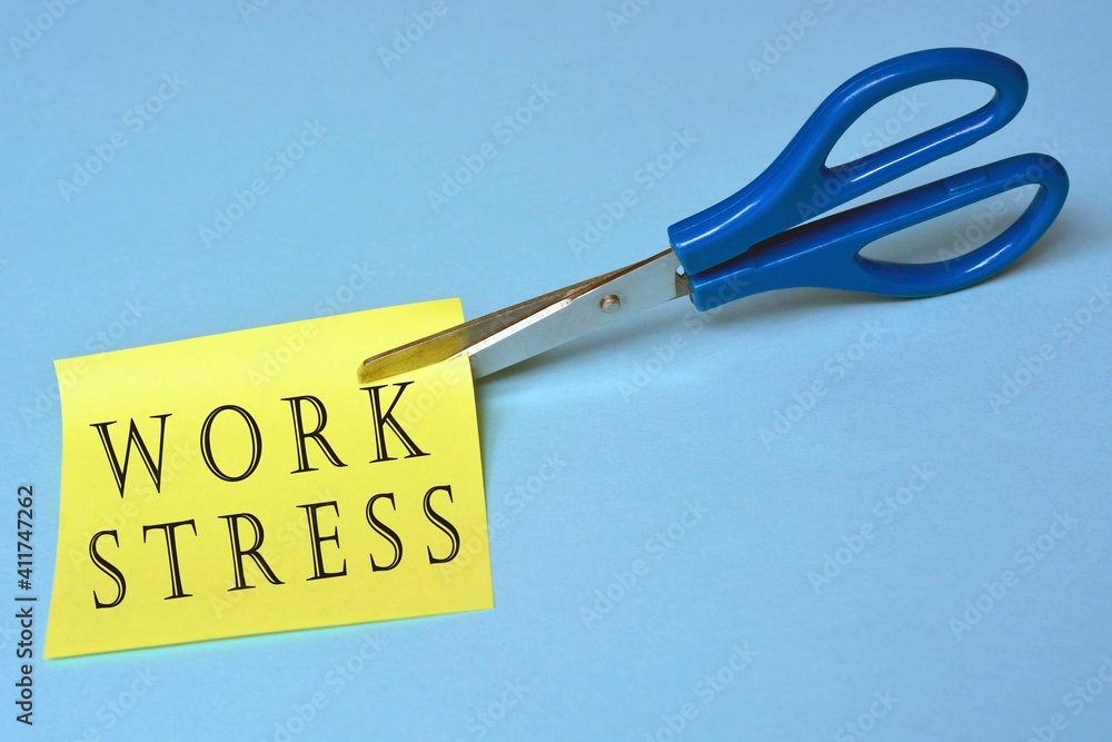 Scissors that cut yellow notepad with work stress text on a blue background Scissors that cut yellow notepad with work stress text on a blue background