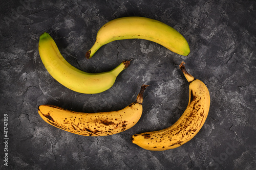 Quadro em tela Comparison of ripe bananas with black patches and slightly green bananas on blac