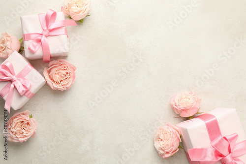 Gift boxes and roses on white textured background, space for text