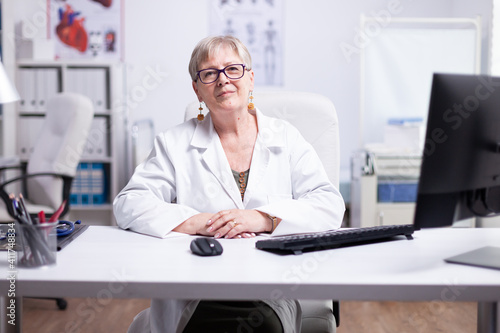 Smiling senior physician doctor wearing white coat consulting online patient via video call looking at camera speaking cam do distance video chat, telemedicine and e-health concept, webcam