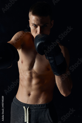 sports guy on a black background in boxing gloves inflated torso cropped view  © SHOTPRIME STUDIO