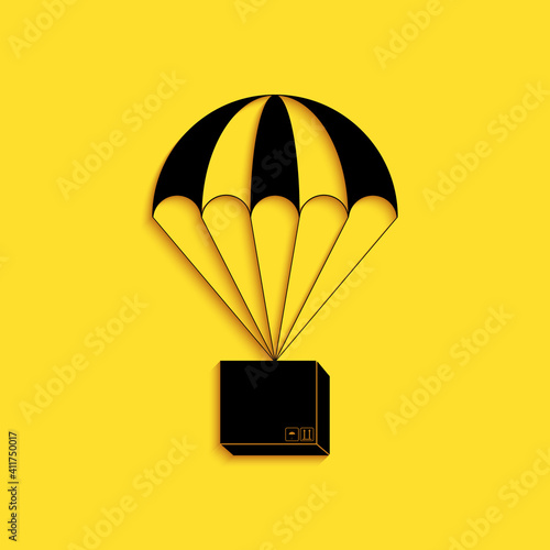 Black Box flying on parachute icon isolated on yellow background. Parcel with parachute for shipping. Delivery service, air shipping concept, bonus. Long shadow style. Vector.