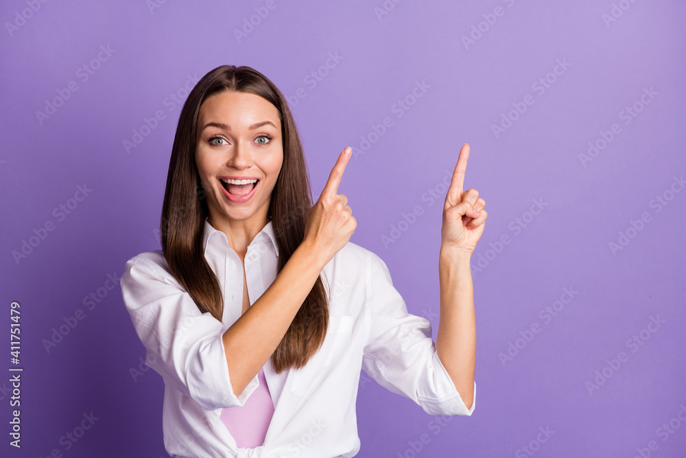 Photo of excited crazy girl indicate forefingers up empty space wear white shirt isolated purple color background Photo of excited crazy girl indicate forefingers up empty space wear white shirt isolated purple color background