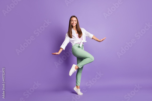 Photo portrait full body view of cute girl standing on one leg isolated on vivid purple colored background