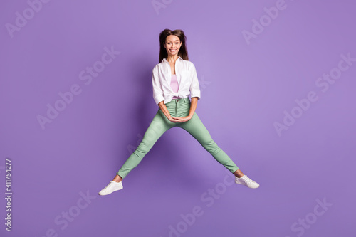 Photo portrait full body view of cheerful girl jumping up isolated on vivid purple colored background