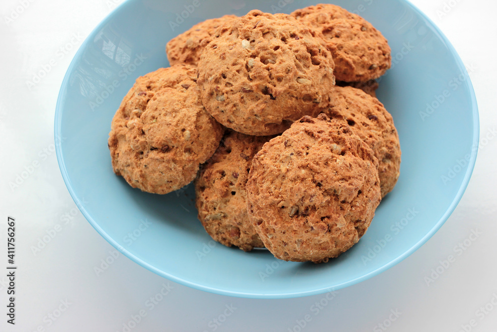Homemade oatmeal cookies in a blue bowl on white table. Overhead view of oat biscuits on white background with copy space Homemade oatmeal cookies in a blue bowl on white table. Overhead view of oat biscuits on white background with copy space