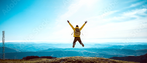 Fotografia Happy man with open arms jumping on the top of mountain - Hiker with backpack ce