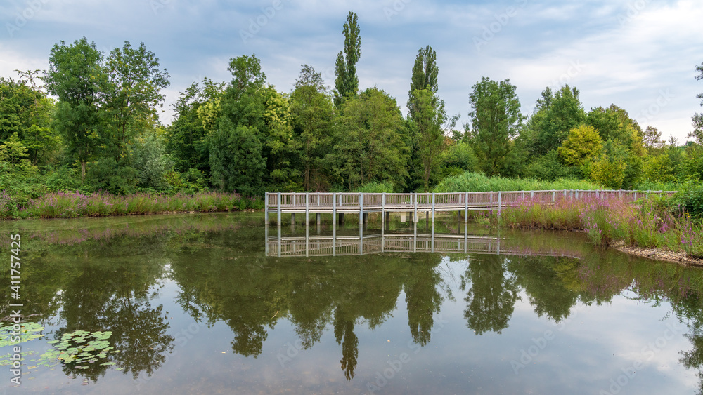 A lake with a pier leading into it, seen at the Nordsternpark, Gelsenkirchen, North Rhine-Westfalia, Germany