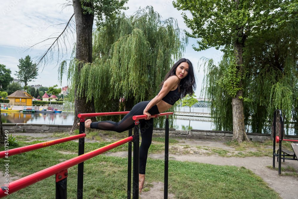 Young fitness woman in sportswear performing exercises on the horizontal bar for perfect body.
