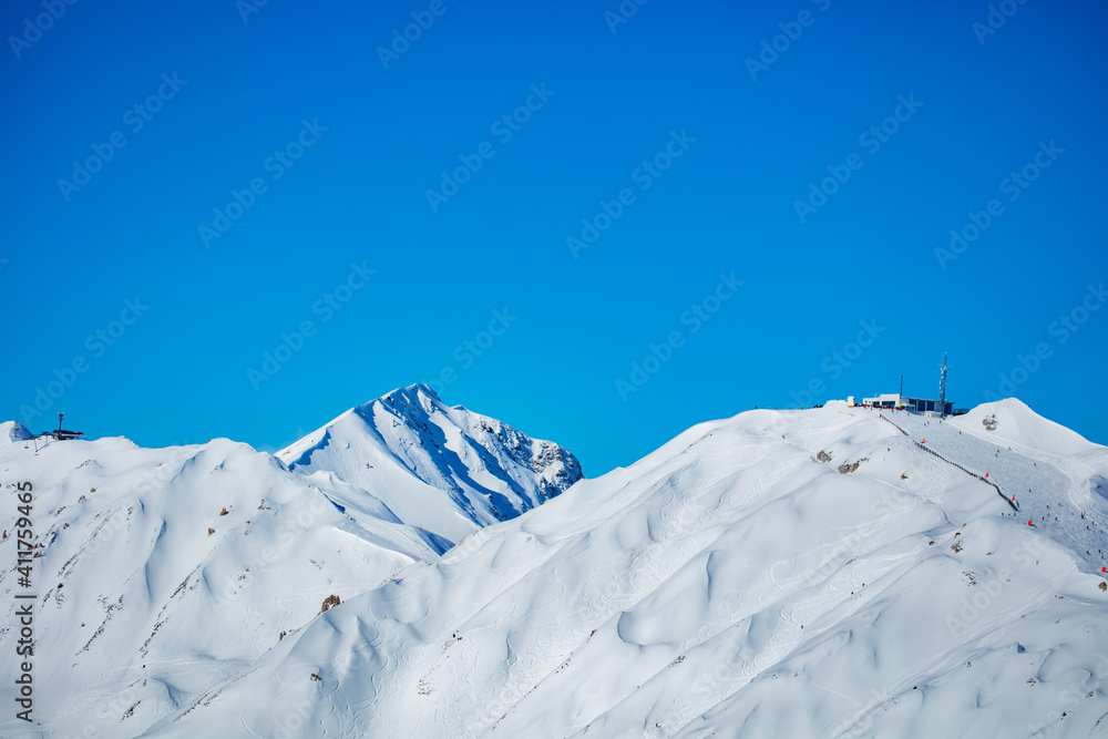 Peaks of high French alps covered with snow at winter over blue sky