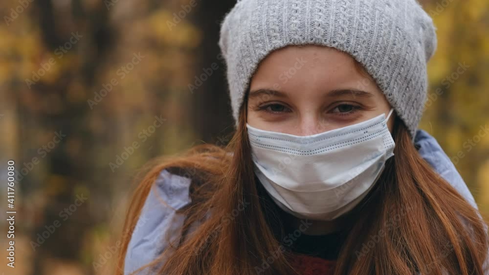 Portrait of young girl in protective mask on autumn trees background Portrait of young girl in protective mask on autumn trees background
