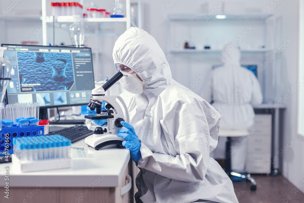 Naklejka premium Team of scientist working on developing a vaccine for coronavirus in laboratory. Chemist researcher during global pandemic with covid-19 checking sample in biochemistry lab