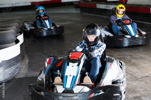 Εκτύπωση καμβά Group of male and females in helmets driving racing cars at kart track