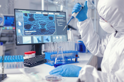 Biochemist man taking sample of liquid holding automatic pipette .Chemist in modern laboratory doing research using dispenser during global epidemic with covid-19.