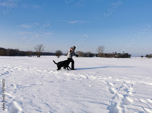Dziecko bawiące się z psem na świeżym powietrzu zimą , błękitne niebo, mroźne powietrze, dużo sniegu