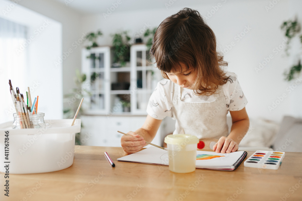 Kids painting watercolor rainbows at table at home Kids painting watercolor rainbows at table at home