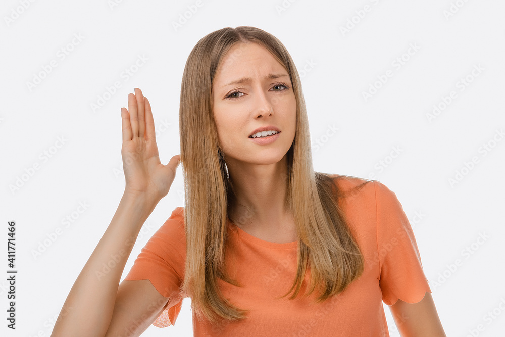 A hard of hearing young beautiful woman putting her hand to ear and listens. The concept of secrecy, eavesdropping A hard of hearing young beautiful woman putting her hand to ear and listens. The concept of secrecy, eavesdropping