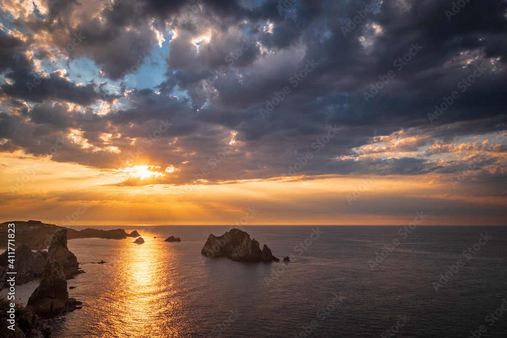 Beautiful Sunset with cloudy sky at the rugged rocky coast of Liencres with Urros and clouds, Northern Spain