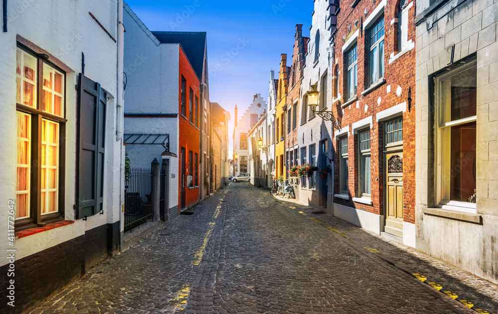Fototapeta premium Narrow cobblestone street with traditional houses in medieval city center of Bruges, Belgium.