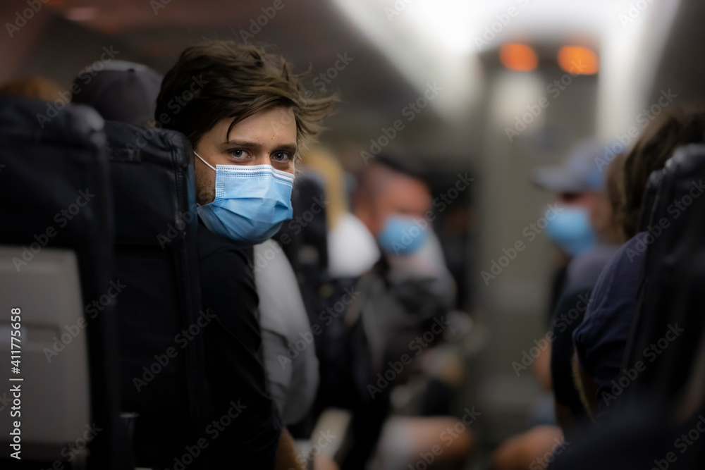 Man wearing medical face mask inside airplane during flight to protect against coronavirus. new normal concept, covid 19 and virus personal protection, mandatory masks, Man wearing medical face mask inside airplane during flight to protect against coronavirus. new normal concept, covid 19 and virus personal protection, mandatory masks,