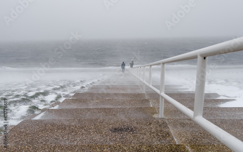 People standing next to the sea, during a blizzard in North Holland, Netherlands photo