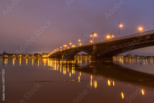 Fototapeta Naklejka Na Ścianę i Meble -  Beleuchtete Brücke über den Rhein bei Mainz an einem Winterabend mit Hochwasser