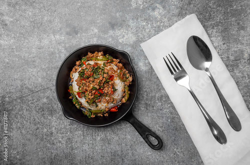 Top view Rice topped with stir-fried minced pork and basil in mini black pan., Popular Thai street food.