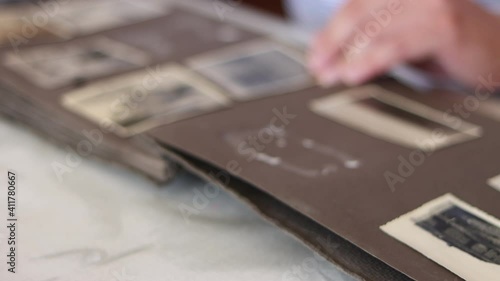 Man flips through the pages of an old album and looks through photographs.