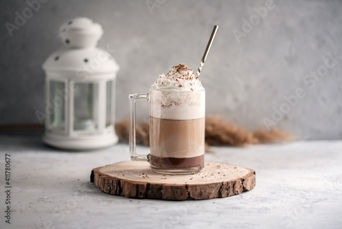 Coffee cocktail mocha with whipped cream on a wooden tray on a stone gray background. Delicious homemade sweet dessert of coffee with milk and cocoad.