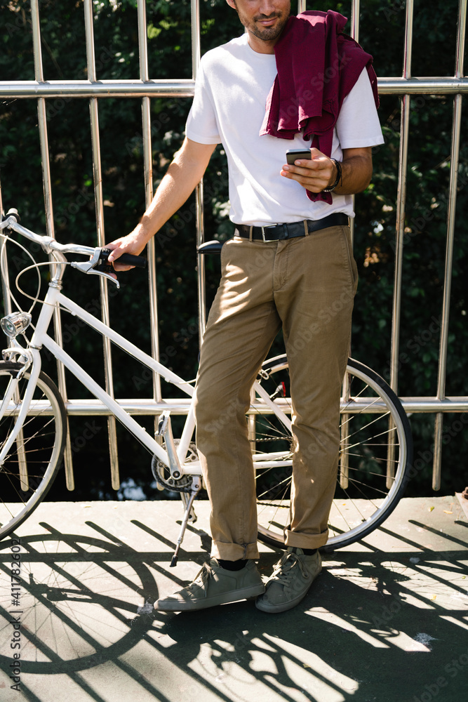 Caucasian man standing by bicycle and using moblie phone Caucasian man standing by bicycle and using moblie phone