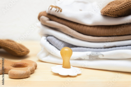 pacifier dummy, clothes, and toys for the newborn on a wooden chest of drawers