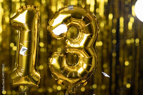 Gold foil number 13 thirteen festive balloon on a yellow background. The concept of birthday, anniversary, date.