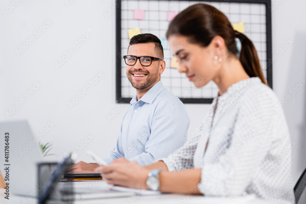 happy businessman in glasses looking at businesswoman on blurred foreground happy businessman in glasses looking at businesswoman on blurred foreground