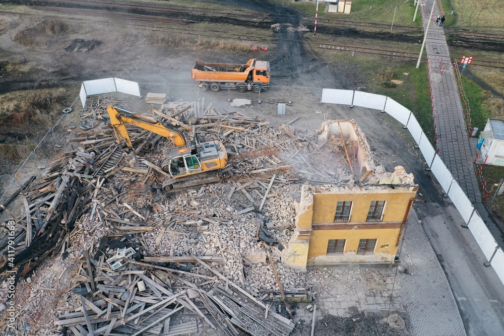 Yellow excavator destroys building. Heavy duty machine is demolishing a brick building. Demolition of the building . Demolition construction work aerial drone photo Yellow excavator destroys building. Heavy duty machine is demolishing a brick building. Demolition of the building . Demolition construction work aerial drone photo