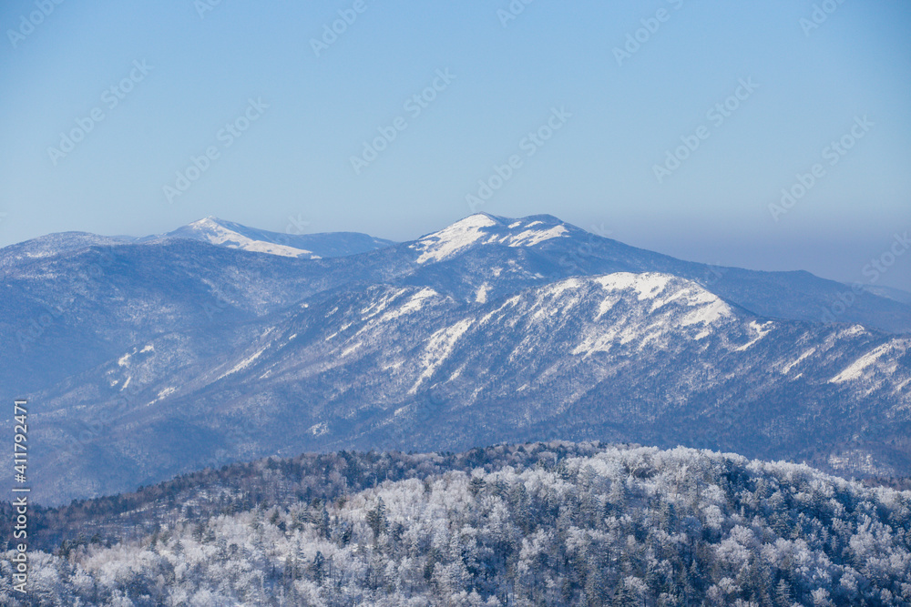 Beautiful winter landscape. The peaks of the snow-capped mountains are buried in morning fog.